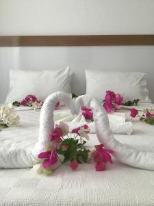 Una cama con dos toallas y flores. en Altunakar 1 Hotel en Didim