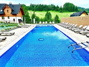 a large swimming pool with chairs and a house at Bury Miś in Jaworki