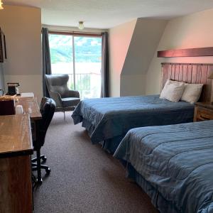 a hotel room with two beds and a desk and a chair at Three Valley Lake Chateau in Revelstoke