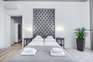 a white bedroom with a large bed with white pillows at Aparthotel 1899 in Szczecin