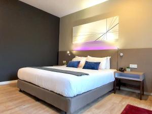 a bedroom with a large bed with blue pillows at Empire Damansara Hotel Suites by Beestay in Petaling Jaya