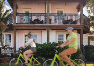 zwei Personen, die vor einem Haus Fahrrad fahren in der Unterkunft Port d'Hiver Bed and Breakfast in Melbourne Beach