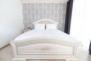 a white bed in a bedroom with a wall at Floros simfonija vilos in Šventoji
