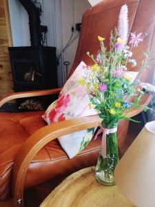 a vase of flowers on a table next to a chair at Domek pod Brzozami - zniżki na Termy Bania! in Czarna Góra