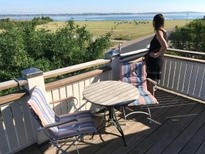a woman standing on a deck with a table and chairs at Villa Wiegand - a room with a view in Holbæk