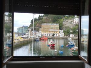 ein Fenster mit Blick auf einen Hafen mit Booten im Wasser in der Unterkunft Hotel Baltico 2 estrellas in Luarca
