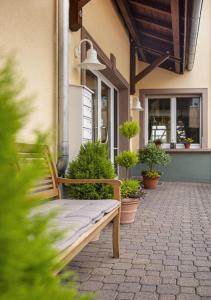 Nidderau的住宿－老麵包店酒店，长凳坐在植物盆栽的建筑物外