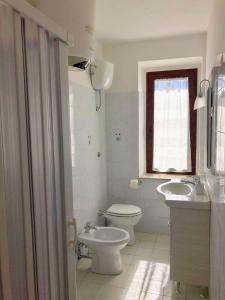 bagno con servizi igienici, lavandino e finestra di La Casa del Villanu a Pitigliano
