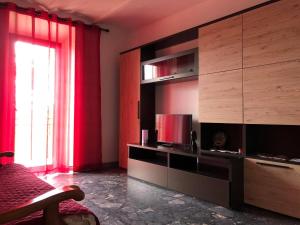 a living room with a television and red curtains at La Casa del Villanu in Pitigliano