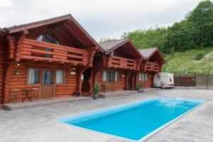 a log cabin with a swimming pool in front of a house at Villa Frans și Căbănuțe in Eşelniţa