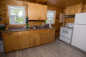 cocina con armarios de madera y nevera blanca en North Rustico Motel & Cottages en North Rustico