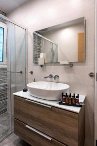 ein Badezimmer mit einem weißen Waschbecken und einem Spiegel in der Unterkunft Lux 1-bedroom apartement next to the sea in Voula in Athen
