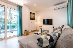 a living room with a couch and a tv at Lux 1-bedroom apartement next to the sea in Voula in Athens