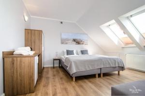 ein weißes Schlafzimmer mit einem Bett und Fenstern in der Unterkunft Villa Chrobry in Mielno