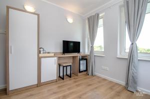 ein Wohnzimmer mit einem TV auf einem Schreibtisch vor einem Fenster in der Unterkunft Villa Chrobry in Mielno