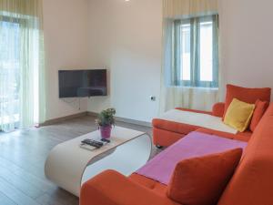 ein Wohnzimmer mit orangefarbenen und weißen Möbeln und einem Flachbild-TV in der Unterkunft Apartments Windrose in Kotor