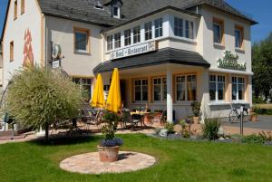 a hotel with a patio with a table and umbrellas at Haus Waldesruh in Hollnich