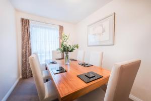 une salle à manger avec une table en bois et des chaises blanches dans l'établissement The Knight Residence by Mansley, à Édimbourg