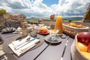 una mesa con comida y zumo de naranja en el balcón en La Charmeraie en Montpeyroux