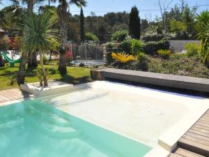 - une piscine dans une cour avec des palmiers dans l'établissement Villa Carroubier, à La Londe-les-Maures