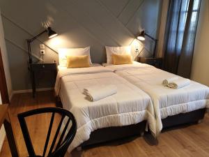 a bedroom with a large bed with white sheets and yellow pillows at Aigaion Guesthouse in Therma