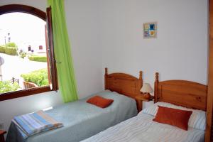 two beds in a room with a window at Apartamento en el mar con terraza in Fornells