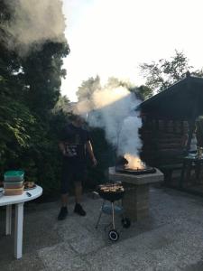 Een man kookt eten op een grill. bij Z&T Apartmanok in Siófok