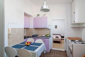 uma cozinha com armários roxos e uma mesa com uma tigela de fruta em Apartment in centre with huge terace em Pula