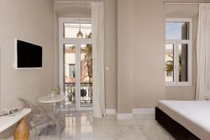 a white bedroom with a bed and a table and a window at 5 Hermoupolis Concept Sites in Ermoupoli