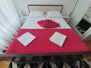 een rood en wit bed met 2 kussens erop bij AS Apartments Rafailovici in Rafailovici