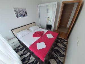 AS Apartments Rafailovici في رفايلوفيتشي: غرفة نوم مع سرير مع بطانية حمراء عليه