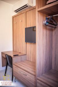 a wooden cubicle with a desk and a tv at MAIOR NOTA - 2 Quartos com AR CONDICIONADOS SPLIT, Air Fryer, Wi-Fi, Netflix, Disney Plus, Star Plus, HBO Max, Guarda Sol, Carrinho com Cadeiras de Praia, Churrasqueira, Rede para Descanso e Chuveirão - 8 pessoas - CONFORTO Máximo! in Guarapari