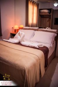 a large bed with white sheets and pillows on it at MAIOR NOTA - 2 Quartos com AR CONDICIONADOS SPLIT, Air Fryer, Wi-Fi, Disney Plus, Star Plus, HBO Max, Guarda Sol, Cadeiras de Praia, Caixa Térmica, Churrasqueira, Rede para Descanso e Chuveirão - 8 pessoas - CONFORTO Máximo - Melhor Localização!! in Guarapari