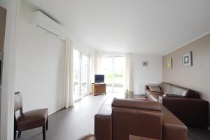 een woonkamer met een bank en een tv bij Chalet 15 (Resort Venetië) in Giethoorn