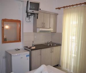 a small kitchen with a sink and a tv on the wall at Sea La Vie - Studios Maria in Limenaria +40 photos