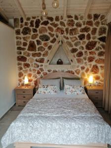 1 dormitorio con 1 cama grande en una pared de piedra en Oliveways, en Liapades