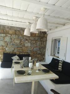ein Esszimmer mit einem Tisch und einer Steinmauer in der Unterkunft PEQUEÑA CASA CERCA DE MIKONOS CIUDAD in Mykonos Stadt
