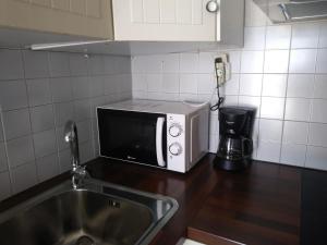 a microwave sitting on a kitchen counter next to a sink at PEQUEÑA CASA CERCA DE MIKONOS CIUDAD in Mikonos