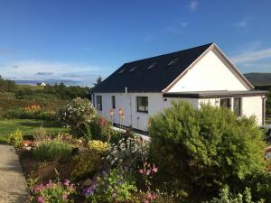 una casa blanca con techo negro y algunas flores en Skye Getaways Self Catering Accommodation, en Dunvegan