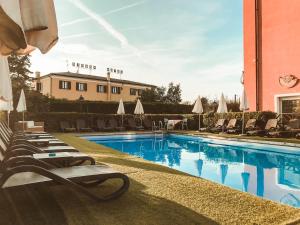 a swimming pool with lounge chairs and a building at Hotel Benacus in Lazise