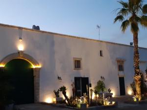 un edificio con una palmera delante de él en Masseria Dimora del viandante - by Click Salento en Sogliano Cavour