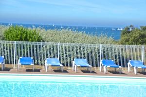 レ・サ​​ーブル・ドロンヌにあるAppartements front de Mer SABLES D'OLONNEのスイミングプールの横の青い椅子