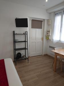 a room with a tv on the wall and a table at Petit studio à BORDEAUX CHARTRONS / JARDIN PUBLIC (6) in Bordeaux +2 photos