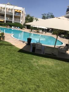 a swimming pool with chairs and an umbrella at Royal Park Eilat - Garden Apartment by CROWN in Eilat