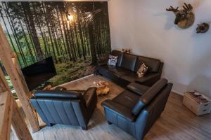 sala de estar con 2 sillas de cuero y sofá en Ates Hütte, en Ilsenburg