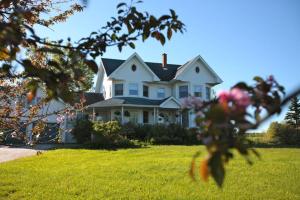 une maison blanche sur une pelouse avec des fleurs roses dans l'établissement Twin Peaks B&B, à Mindemoya