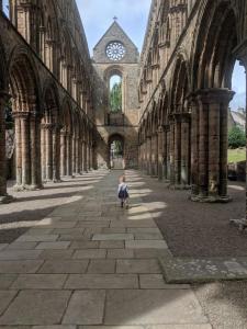 a small child walking through a building with a clock tower at Marys Garden View South in Jedburgh