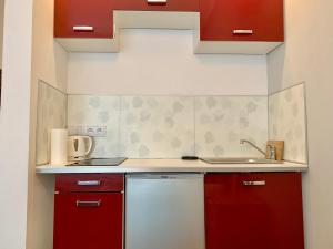 a small kitchen with red cabinets and a sink at Studio in Center in Krakow