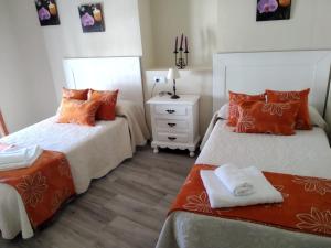 1 dormitorio con 2 camas con almohadas de color naranja y mesita de noche en Apartamento Fregenal Centro R&S, en Fregenal de la Sierra