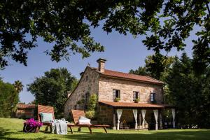 een oud stenen huis met 2 stoelen en een tafel bij Casa da Muiñeira in Cambados